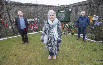 Tres supevivientes del orfanato El Hogar en Tuam posan en el monumento construido en recuerdo a los 800 esqueletos de niños que aparecieron en 2014 en este convento regentado por monjas del Buen Socorro. (Paul FAITH / AFP)