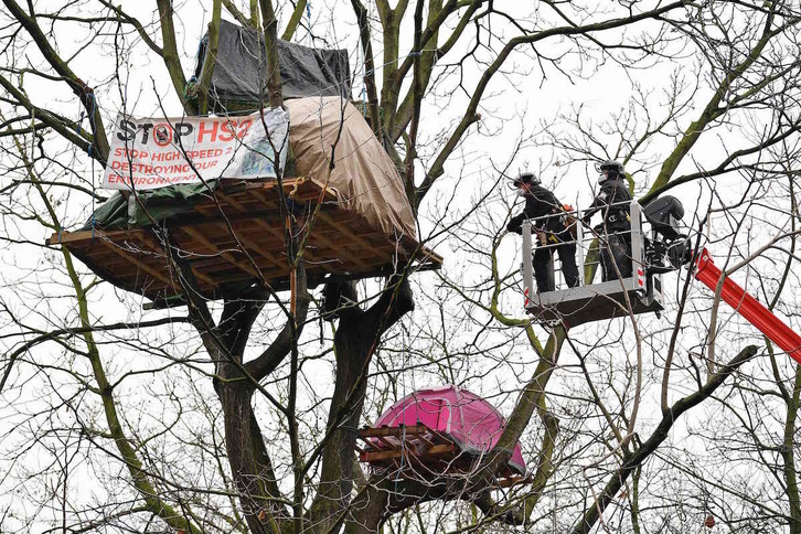 Policías tratan de bajar a los activistas instalados en tiendas de campaña en los árboles del parque Euston. (Justin TALLIS/AFP)