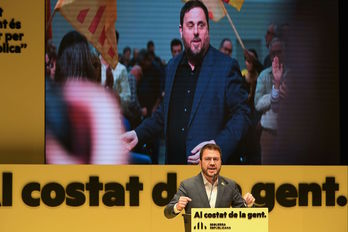 El candidato de ERC, Pere Aragonés, con imágenes del líder del partido, Oriol Junqueras, a su espalda. (Lluís GENÉ/AFP)