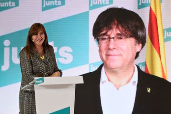 La candidata de Junts, Laura Borràs, con Carles Puigdemont a la espalda. (Josep LAGO/AFP)