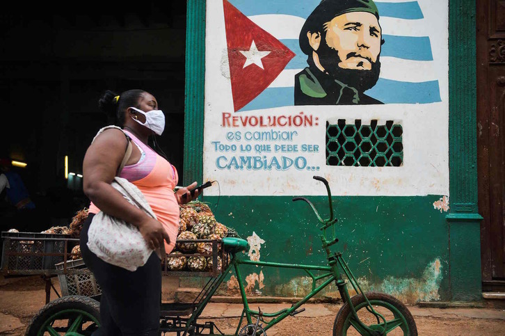 Emakume bat Fidel Castroren omenezko horma-irudi baten ondotik igarotzen, Habanan. (Yamil LAGE/AFP)