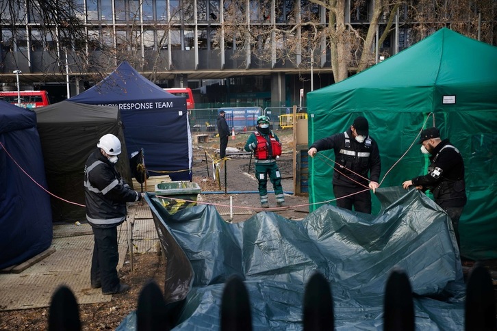 Agentes de Policía tapan con lonas el acceso a los túneles excavados por activistas ecologistas cerca de la estación londinense de Euston. (Tolga Akmen | AFP)