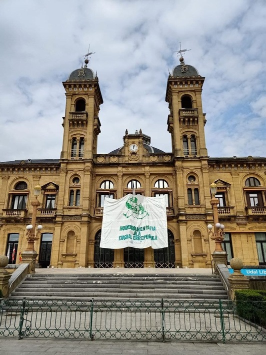 Ehun mugimenduak pankarta handi bat zintzilikatu du Donostiako Udaletxearen fatxadan.