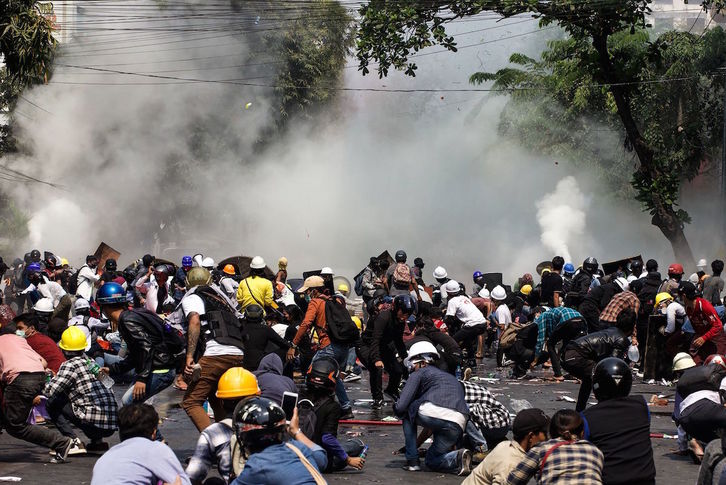 Manifestantes intentan protegerse de los gases lacrimógenos en Mandalay. (AFP)