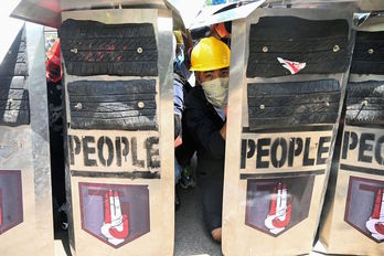 Manifestantes se protegen de la Policía tras sus escudos en las calles de Yangón. (STR/AFP)