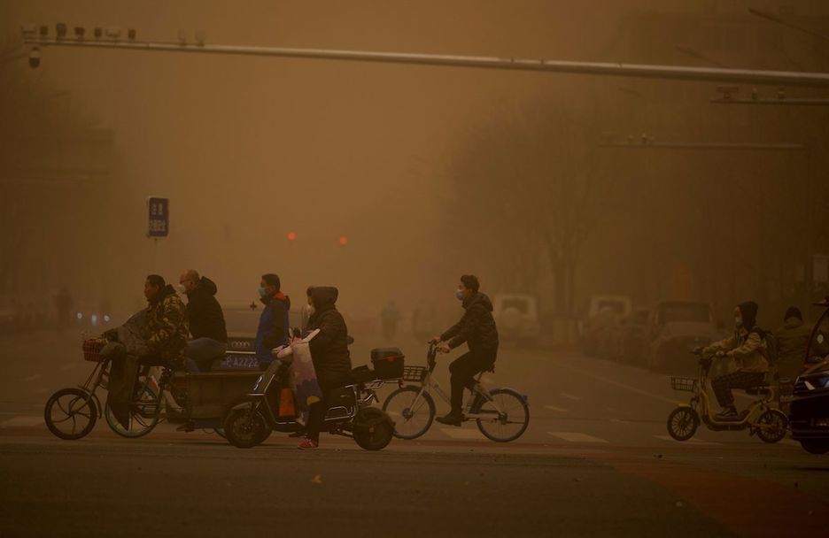 Gente cruzando la carretera durante la tormenta de arena. (Noel CELIS/AFP)