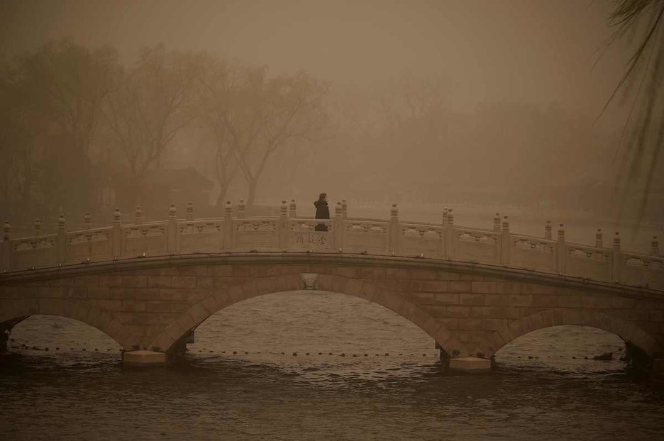 Una mujer cruza el puente del lago Huahai durante la tormenta. (Noel CELIS/AFP)