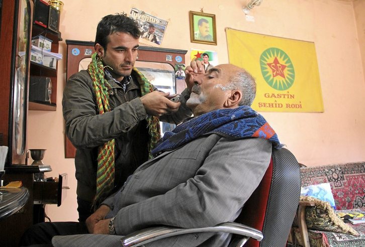 Haidar afeita a un cliente durante el otoño de 2012, cuatro meses después de la marcha de las autoridades de Damasco de los enclaves de mayoría kurda del norte del país. Fotografías: David Meseguer