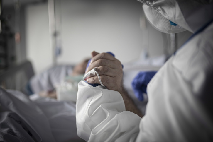Un profesional sanitario agarra la mano a un paciente de covid-19 en el Hospital de Gurutzeta.    (Andoni LUBAKI I FOKU)