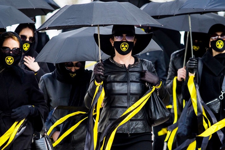 Un grupo de mujeres con mascarillas con el símbolo de radiactividad marchan bajo los paraguas en Minsk –capital de Bielorrusia– para recordar a las víctimas del desastre nuclear de Chernobyl. (AFP)