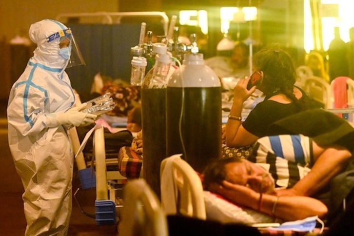 Personal sanitario atiende a pacientes con covid en un salón de banquetes convertido en centro sanitario provisional, en Nueva Delhi. (Prakash SINGH | AFP)