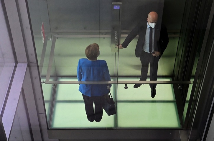 Angela Merkel Alemaniako kantzillerra, bere bizkartzainetako batekin, igogailu batean. (John MACDOUGALL/AFP)