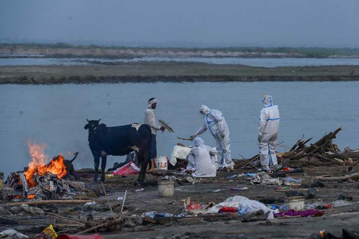 Un equipo de sanitarios con traje de protección supervisa la cremación de víctimas del covid a orillas del río Ganges. (Prakash SINGH / AFP)