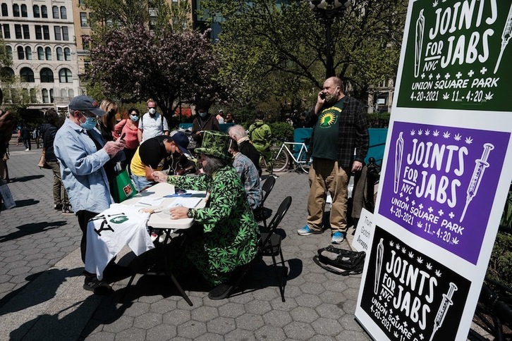 Gente haciendo fila en una plaza de Nueva York para recibir un cigarrillo de marihuana gratis después de mostrar una prueba de que se ha vacunado contra el covid-19. (Spencer PLATT | AFP)