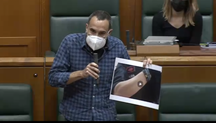 El parlamentario Julen Arzuaga muestra la imagen de un ertzaina con pulsera de Jusapol.