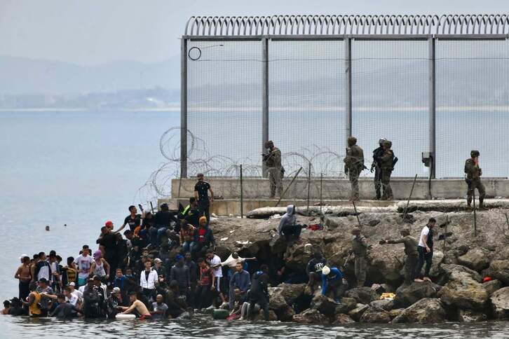 Migrantes y militares en la valla de Ceuta. (Antonio SEMPERE/AFP)