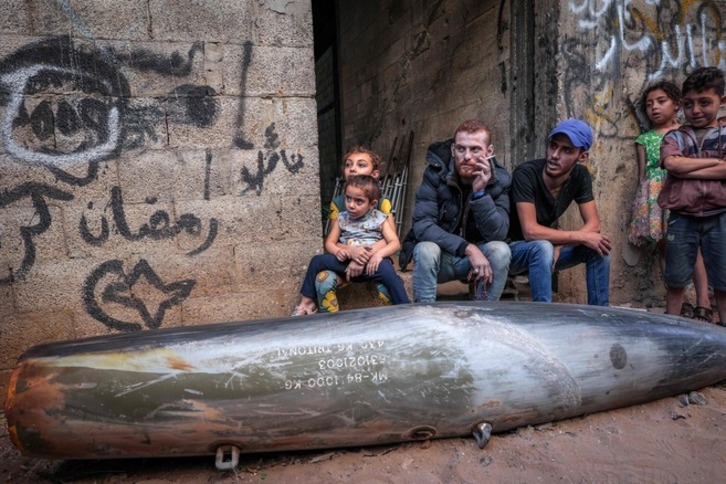 Palestinos sentados este jueves junto a un obús sin explotar lanzado por Israel. (M. ABED/AFP)