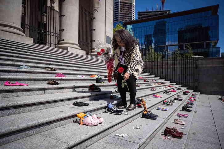 Una mujer indígena coloca en Vancouver una flor en cada uno de los 215 pares de zapatos para recordar a los niños cuyos restos han sido hallados. (Darryl DYCK/THE CANADIAN PRESS/DPA)
