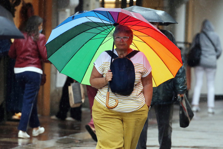 Una mujer paseando por Donibane Lohizune sin máscara a abrigo de un colorido paraguas. (Bob EDME).