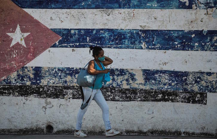 Una mujer pasa frente a una pared con la bandera cubana, en La Habana. (Yamil LAGE/AFP)