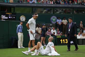 Roger Federer se interesa por el estado de su rival, Mannarino. (Adrian DENNIS/AFP)