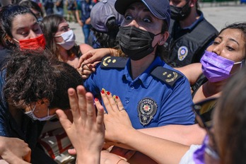 Polizia agente bat emakume batzuei kartelak kentzen saiatzen ari da Turkia Istanbulgo Hitzarmenetik ateratzearen kontrako manifestazio batean, ekainaren 19an. (Bulent KILIC/AFP)