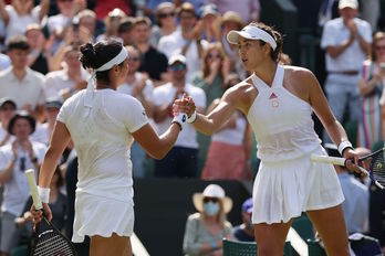 Muguruza y Jabeur se saludan tras el enfrentamiento entre ambas en Wimbledon. (Adrian DENNIS/AFP)