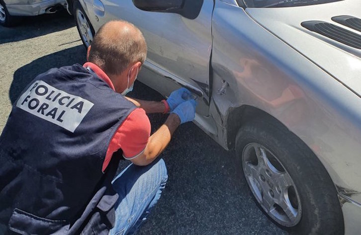 Un policía foral escudriña el coche con el que huyó el presunto autor del crimen machista de Murchante. (NAFARROAKO FORUZAINGOA)