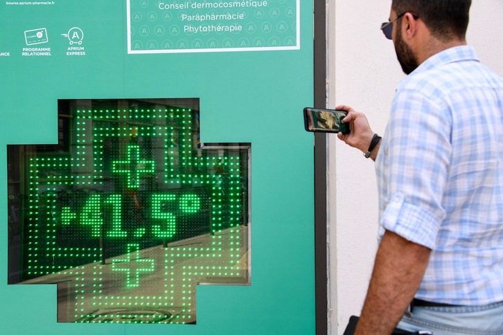 Un peatón toma una fotografía de una pantalla de termómetro que muestra una temperatura de 41,5 grados Celsius en el exterior de una farmacia en París el 25 de julio de 2019. (Bertrand GUAY/AFP)