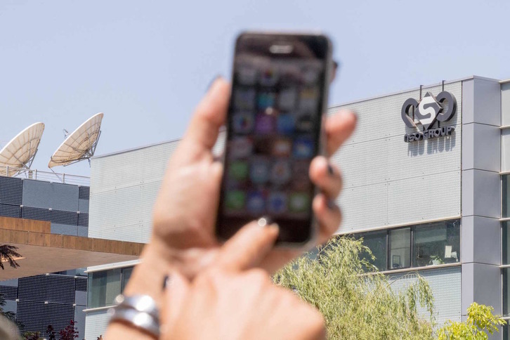 Una mujer sostiene su teléfono móvil frente a la sede de la empresa israelí NSO Group. (Jack GUEZ/AFP)