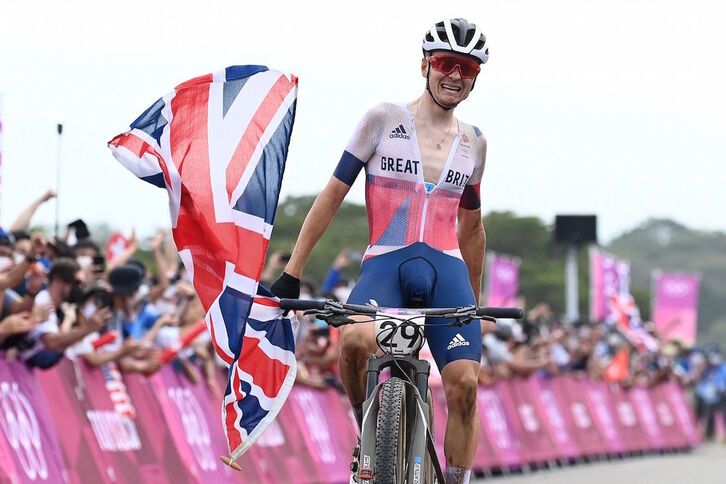 Tom Pidcock cruza la meta con la bandera británica al lograr su triunfo más importante. (Greg BAKER/AFP))