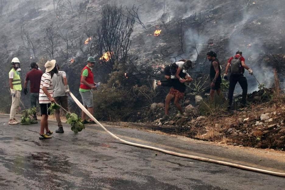 Bomberos y ciudadanos intentan apagar el fuego. (AFP)