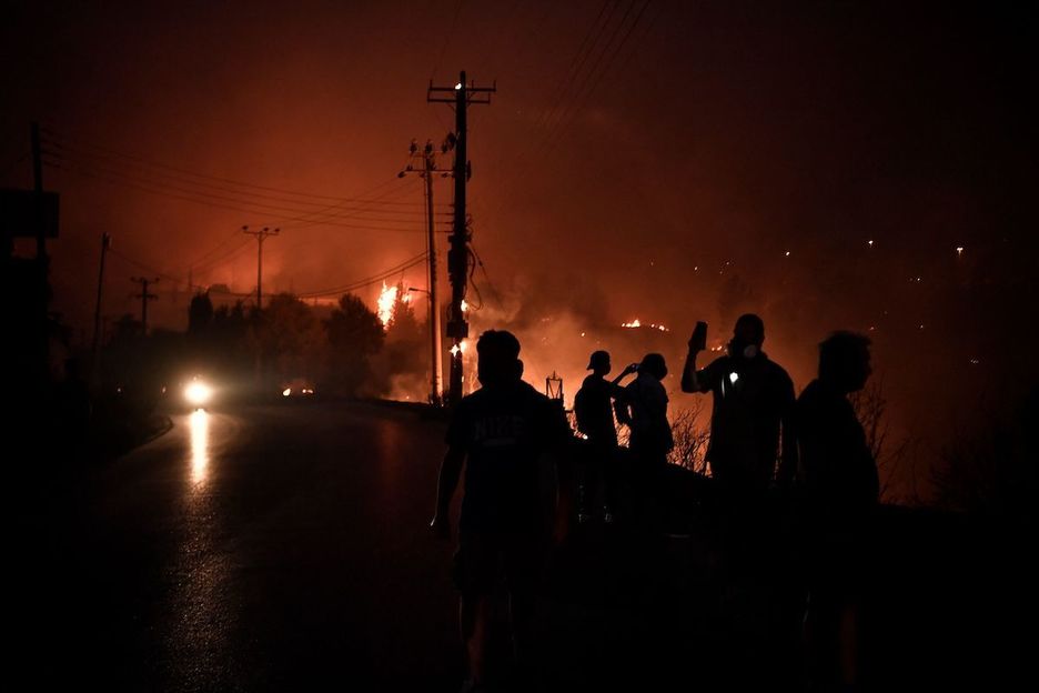Gente entre las  llamas del incendio de Grecia. (Louisa GOULIAMAKI / AFP)