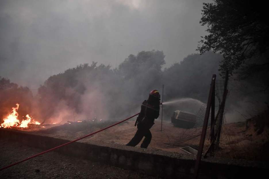 Un bombero intenta apagar el fuego en el bosque de Tatoi cerca de Acharnes, donde estalló el incendio forestal, durante una ola de calor en el país. (Louisa GOULIAMAKI / AFP)