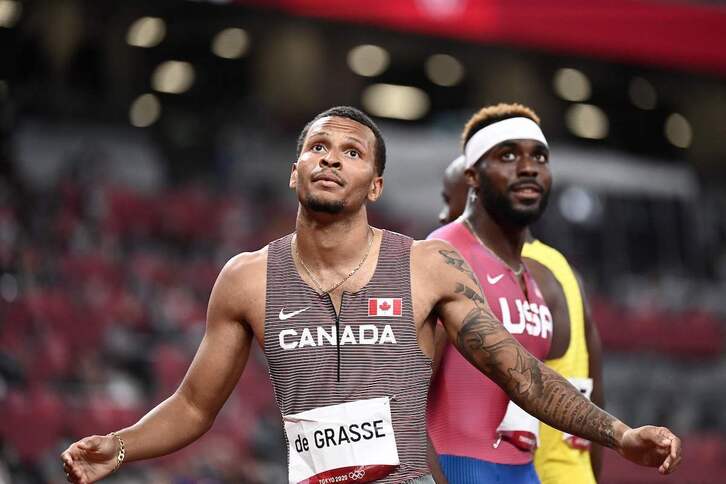 De Grasse saluda a sus rivales tras imponerse en la final de 200 metros. (Jewel SAMAD / AFP)