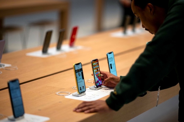 Usuarios mirando teléfonos Apple en una de sus tiendas. (Johannes EISELE | AFP)