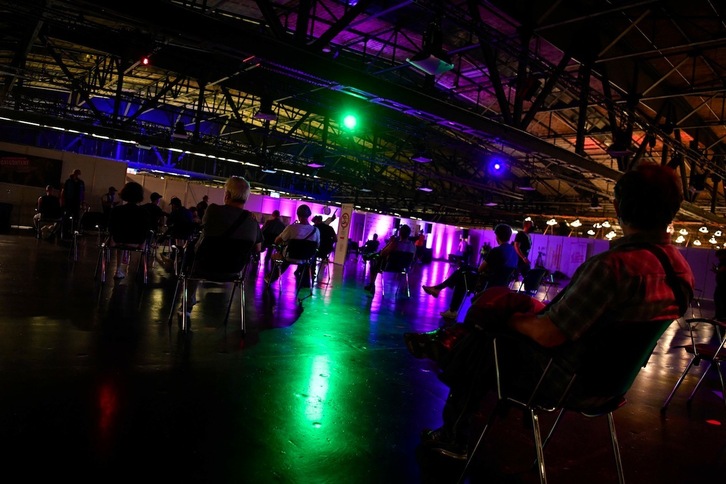 La gente espera a recibir la vacuna contra el covid-19 durante una larga ‘noche de fiesta’ mientras un DJ mezcla la música ambiente en el Arena Club de Treptow, en Berlín. (John MACDOUGALL | AFP)