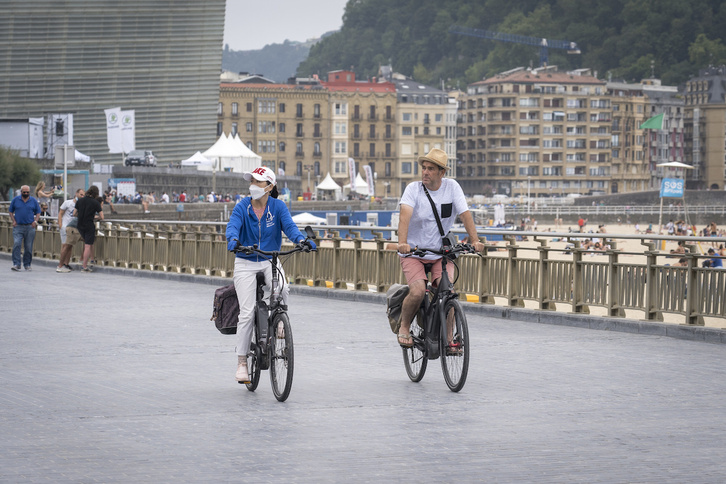 Dos personas circulan en bici por Donostia, una con mascarilla y la otra sin ella. (Gorka RUBIO / FOKU)