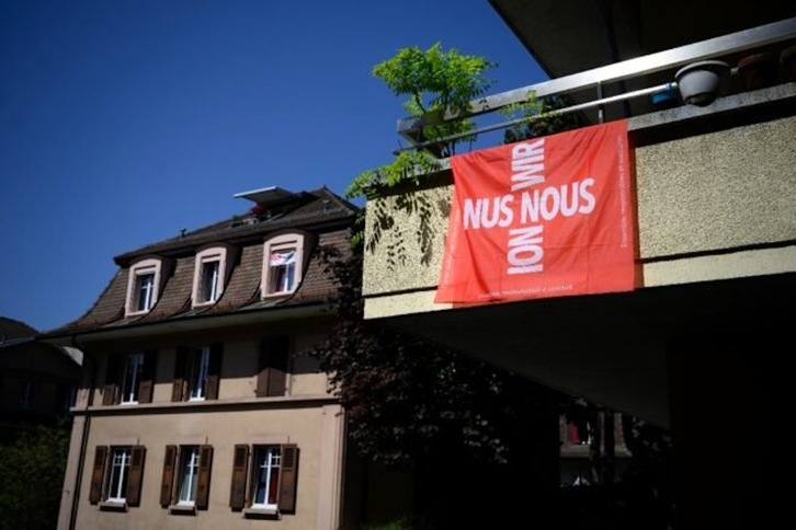Una bandera con la cruz suiza en la que se lee «Nosotros» en las cuatro lenguas oficiales suizas, en un balcón de Lausana. (Fabrice COFFRINI | AFP)