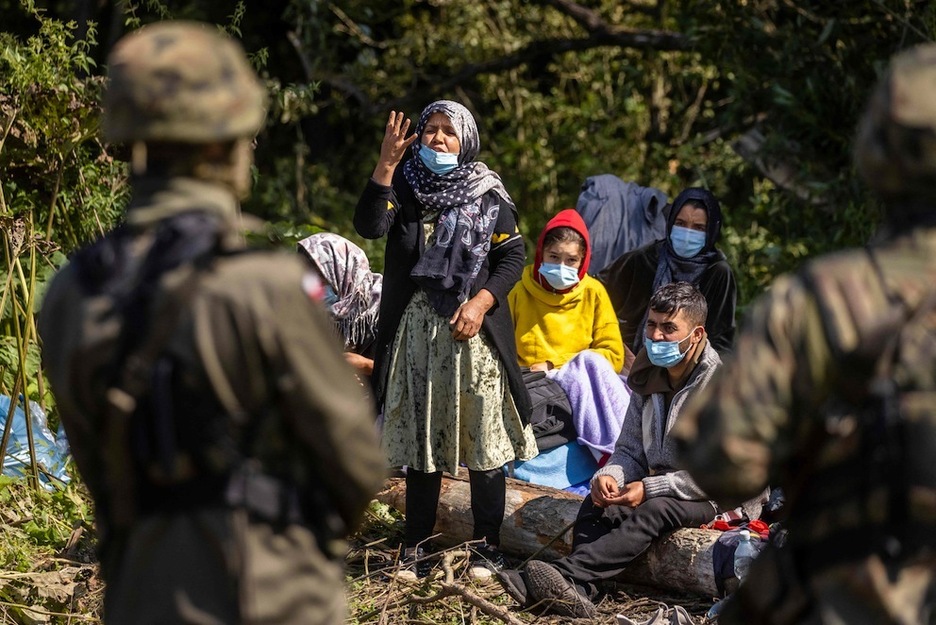 Una mujer habla con un guardia fronterizo polaco mientras están retenidos en la frontera. (Wojtek RADWANSKI | AFP)