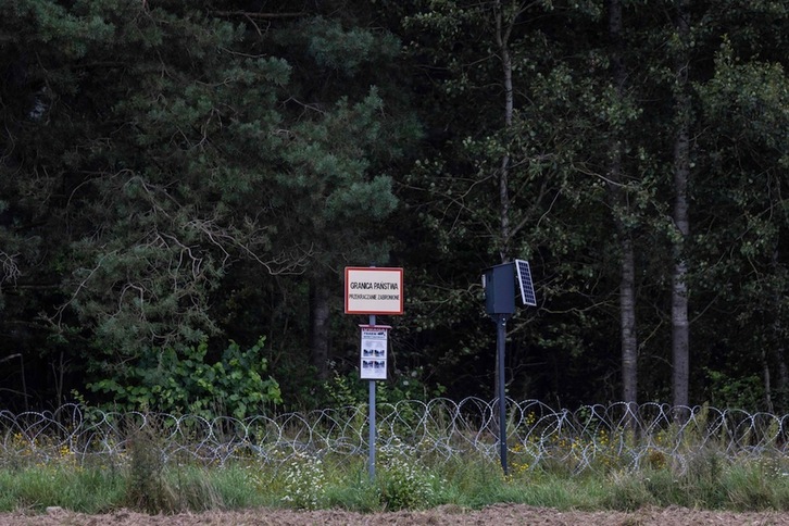 Un letrero que dice «Frontera estatal: prohibido el paso», una cámara de seguridad y alambre de púas en la frontera entre Polonia y Bielorrusia. (Wojtek RADWANSKI | AFP)