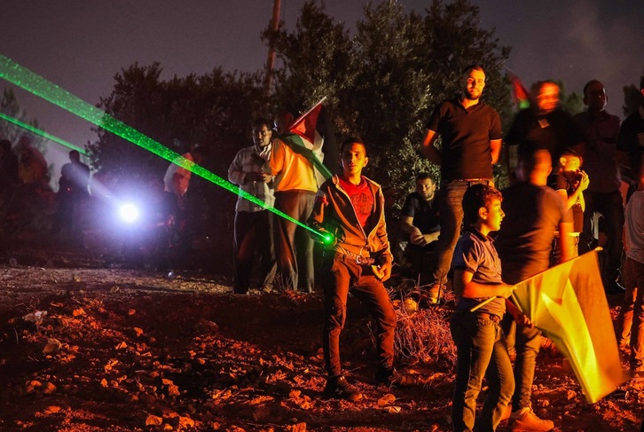 Activistas palestinos usan punteros láser durante una manifestación contra el puesto de avanzada de los colonos israelíes en Eviatar, en la localidad de Beita, el pasado 1 de julio. (Jaafar ASHTIYEH | AFP)