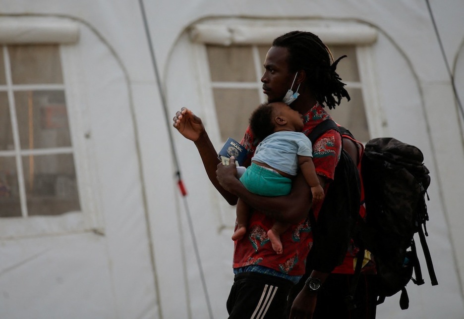 Un hombre con su bebé se dirige al control de documentación en la Estación de Recepción de Migrantes (ESM) de San Vicente, en Metetí. (Rogelio FIGUEROA | AFP) Un hombre con su bebé se dirige al control de documentación en la Estación de Recepción de Migrantes (ESM) de San Vicente, en Metetí. (Rogelio FIGUEROA | AFP)