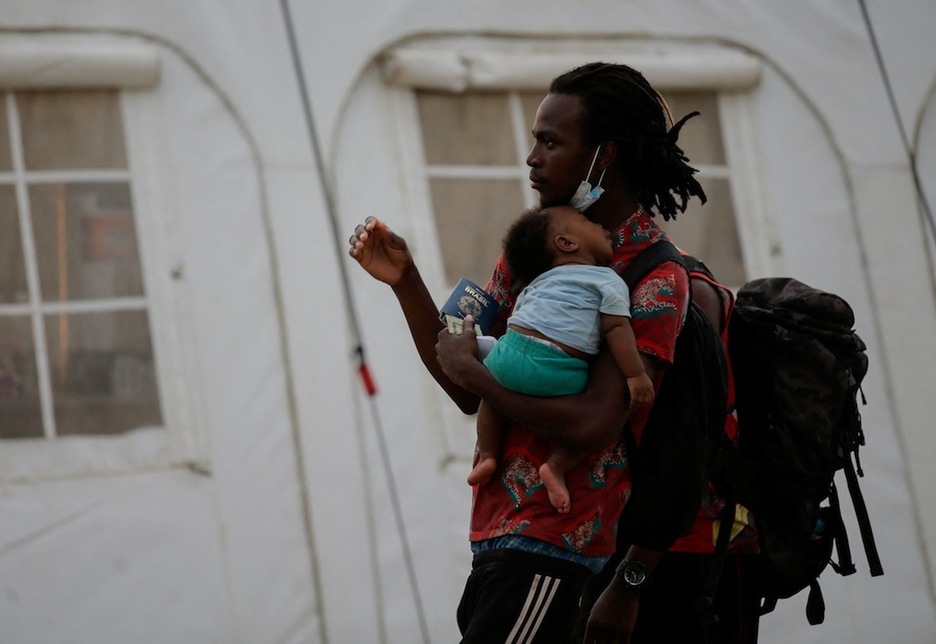 Un hombre con su bebé se dirige al control de documentación en la Estación de Recepción de Migrantes (ESM) de San Vicente, en Metetí. (Rogelio FIGUEROA | AFP)
