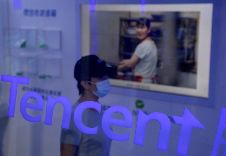 Una mujer pasa junto a un escaparate con el logo de Tencent en la Feria Internacional de Comercio de Servicios de China (CIFTIS) en Pekín. (Noel CELIS | AFP)