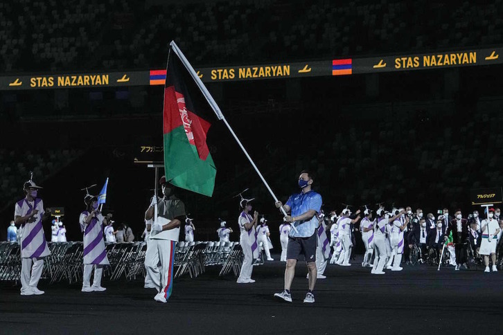 La bandera de Afganistán desfiló en solitario  en la inauguración en homenaje a la ausencia de los dos paratletas que no habían podido volar a Japón. (AFP)
