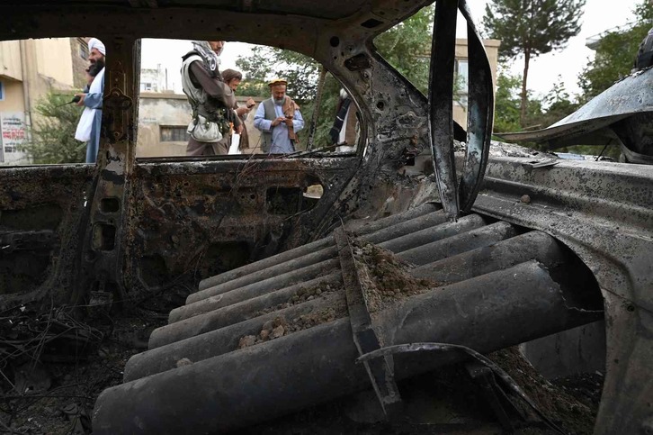 Talibanes junto a un coche calcinado tras el lanzamiento de cohetes en Kabul. (Wakil KOHSAR/AFP) 