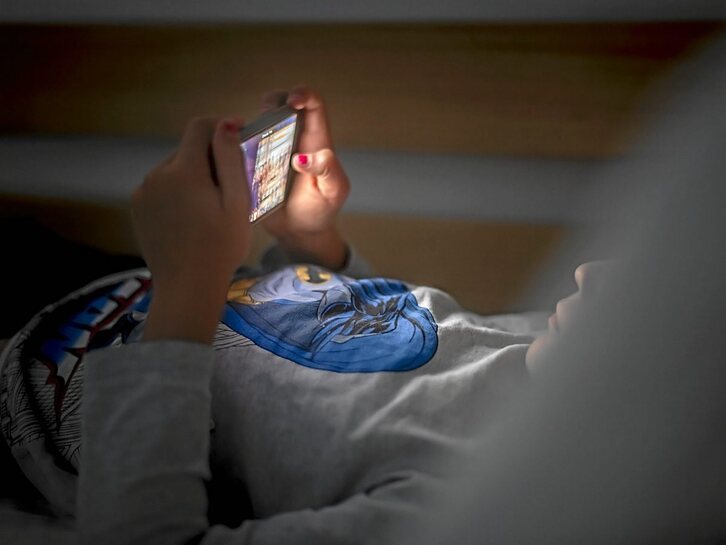 Haur bat ohean, sakelako telefonoari begira. (Jaizki FONTANEDA I FOKU)