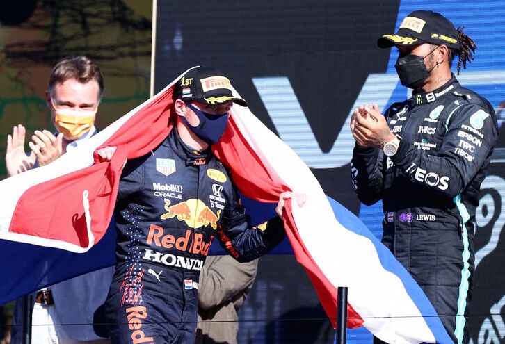 Verstappen, enfundado en la bandera holandesa, es aplaudido por Hamilton (Kenzo TRIBOUILLARD / AFP)