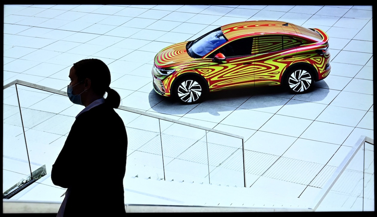 Una mujer pasa junto a una pantalla que muestra un automóvil eléctrico ID.5 de Volkswagen en el Salón Internacional del Automóvil de Múnich. (Christof STACHE/AFP)